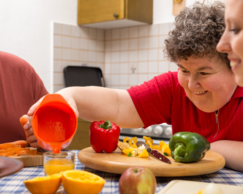 mentally disabled woman with caregivers at the table with lots of vegetables, cooking concept